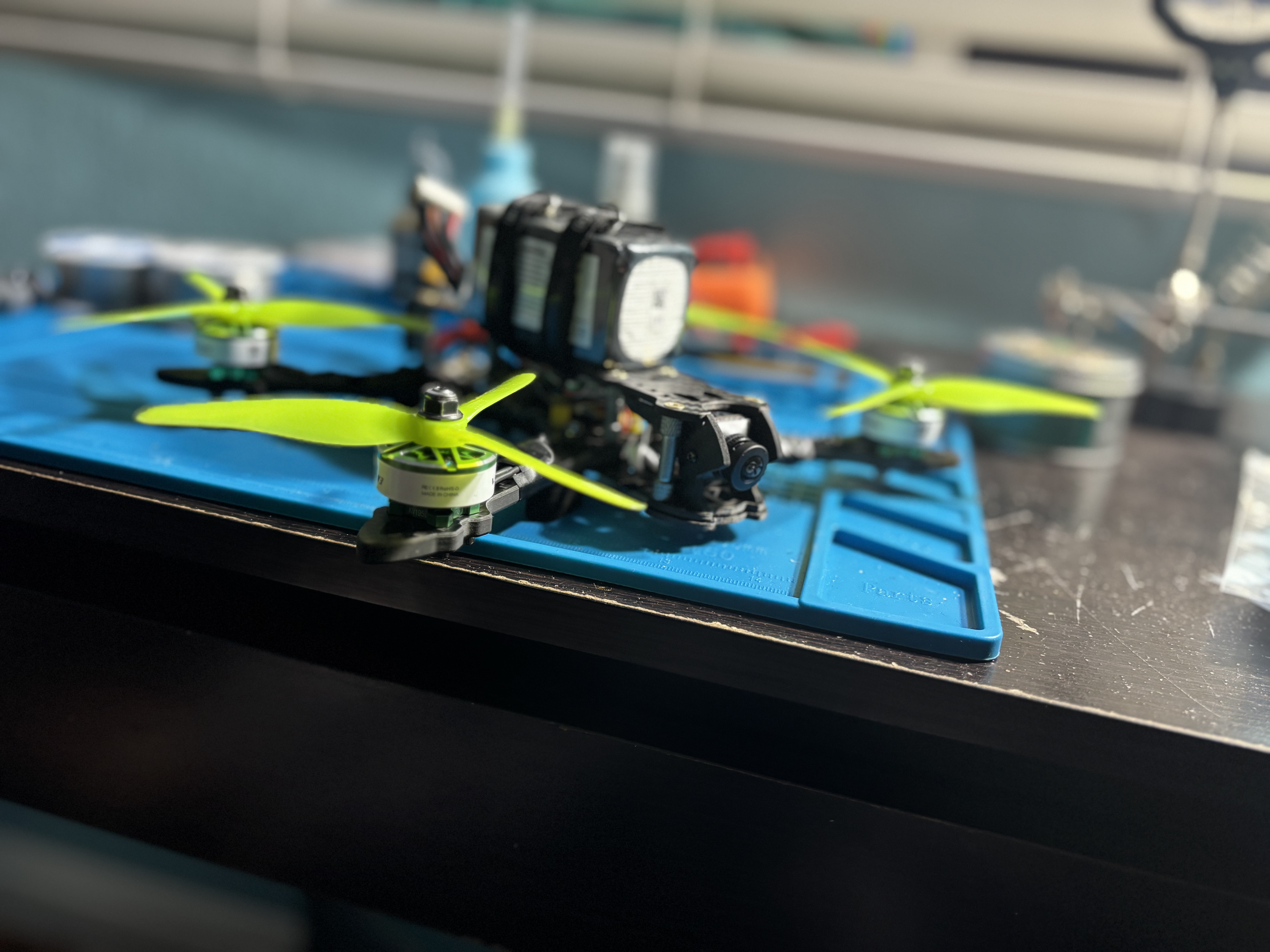 Side profile of the FPV drone on the bench showing the FC/ESC stack and mounted camera
