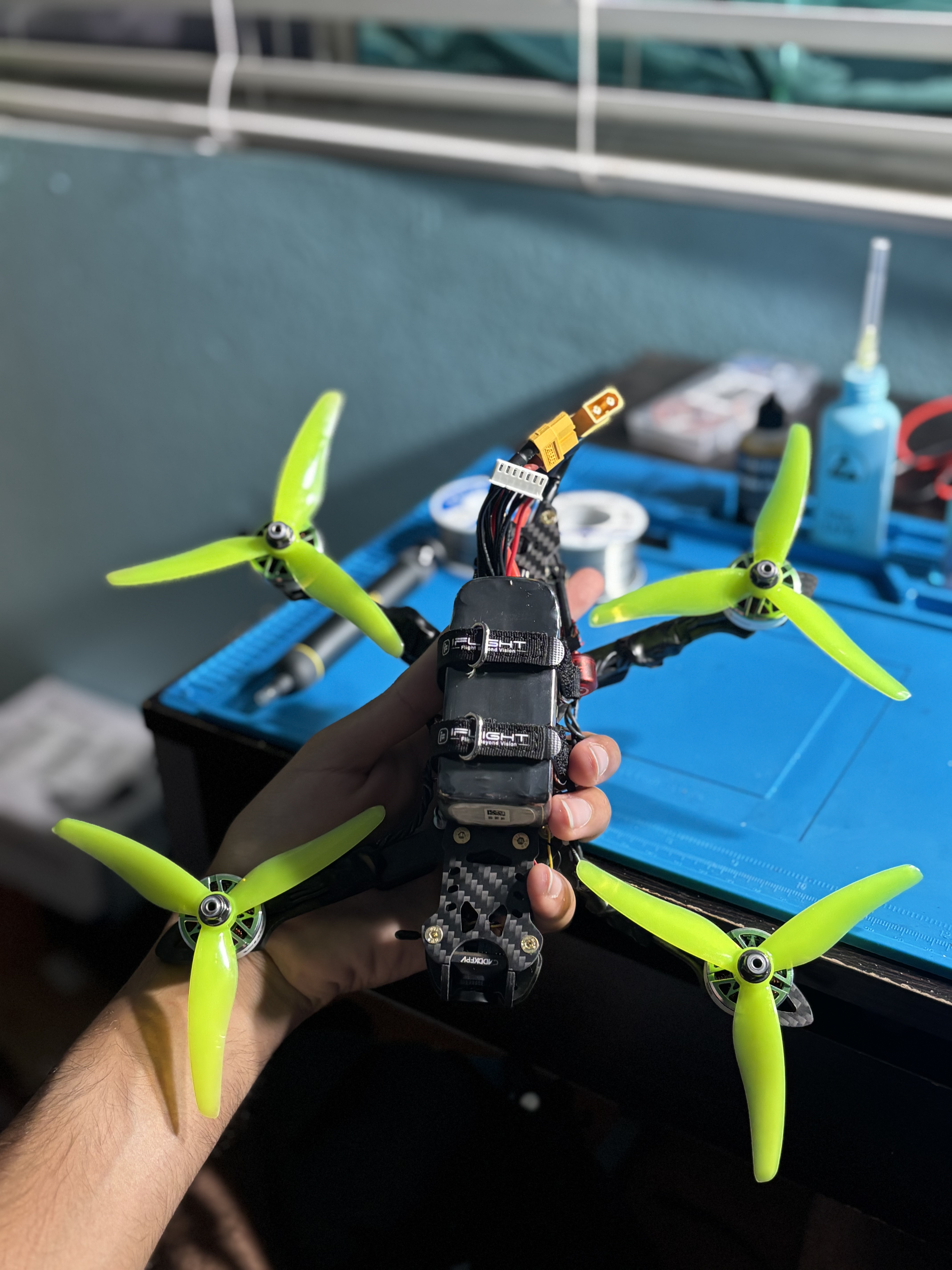 Topside of the FPV drone showing the LiPo battery strap over the FC/ESC stack and the XT60 power lead